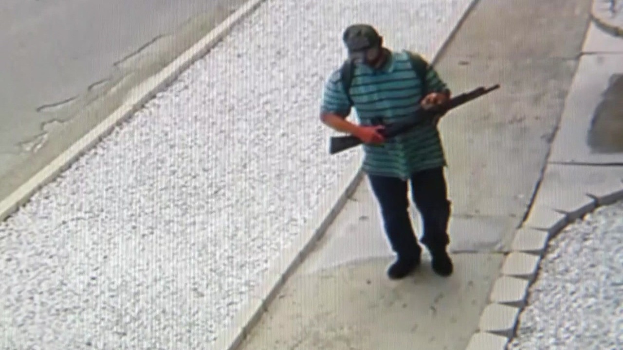 Man seen on surveillance video pointing shotgun at people in...